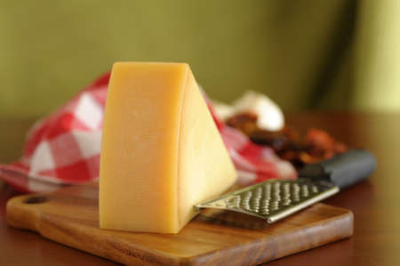 Closeup of a wedge of parmesan cheese on a wooden board.