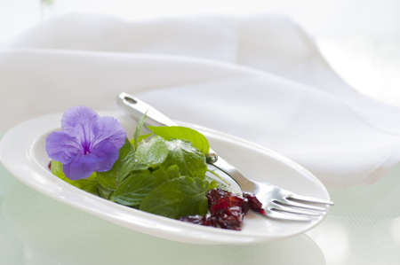 Delicious light salad of fresh greens and dried canberries garnished with an edible flower.の写真素材