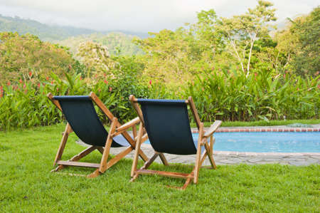 Blue canvas pool chairs overlooking a beautiful tropical landscape in Costa Rica.の写真素材