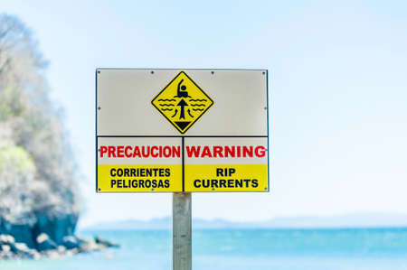 Warning sign for rip currents near an ocean beach.の写真素材