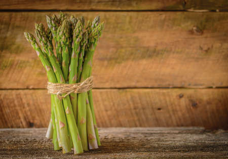 Bunch of fresh asparagus against a rustic wood background.の写真素材