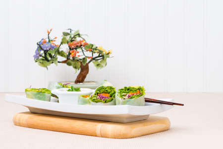 Freshly made vegetarian spring rolls on a white serving plate.
