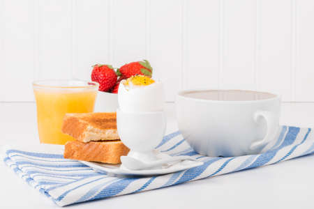 Soft boiled egg with toast served with coffee and juice.