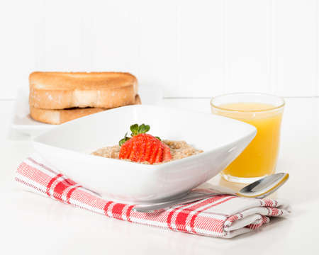 Bowl of hot oatmeal garnished with fresh strawberry.
