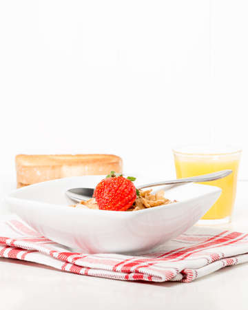 Bowl of breakfast cereal served with toast and orange juice.