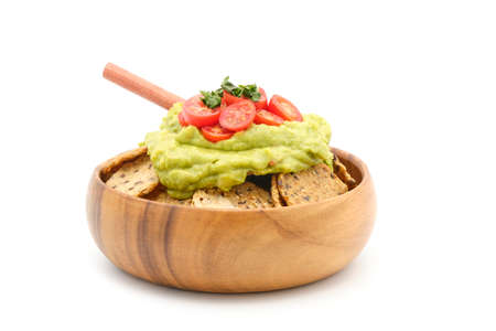 Bowl with wholegrain crackers topped with fresh made avocado dip, tomatoes and basil.