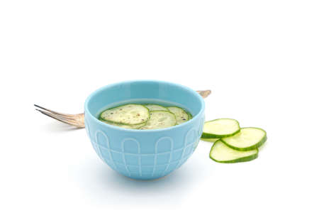 Simple pickled cucumber used as a condiment in a blow ceramic bowl on a white background.の写真素材