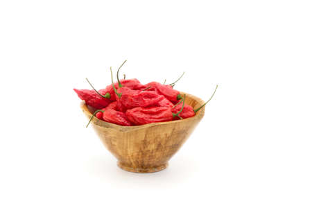 Vibrant red chilis in a wooden bowl photographed on a white background.