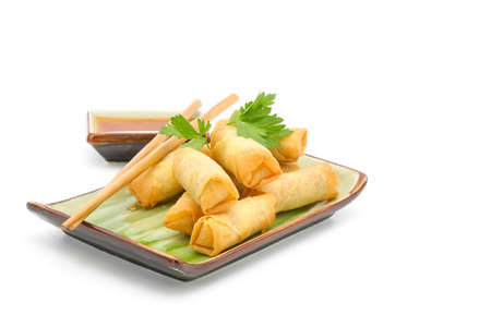 Plate of vegetarian Thai spring rolls served with a spicy dipping sauce on a white background.の写真素材
