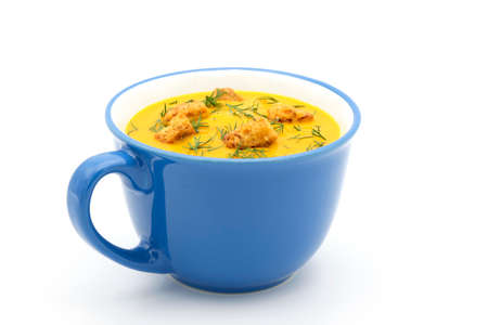 Blue mug of homemade carrot dill soup photographed closeup on a white background.の写真素材