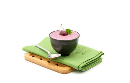Small bowl of cherry flavored Greek yogurt garnished with a whole fresh cherry photographed on a white background.の写真素材