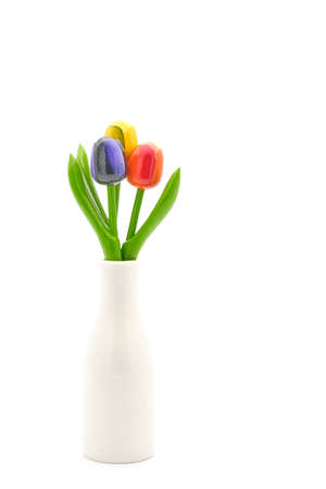 Three colorful artificial wooden tulips in a vase photographed on a while background with ample copy space.の写真素材