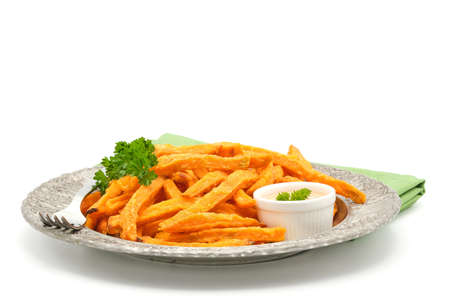 Plate of fresh made sweet potato fries with a garlic aioli photographed on a white background with...