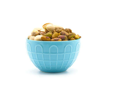 Bowl of fresh roasted and salted pistachios photographed on a white background with ample copy...