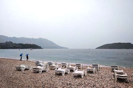 Autumn rain on a deserted beach near the Adriatic Sea. People under umbrellas. September in Montenegro.の写真素材