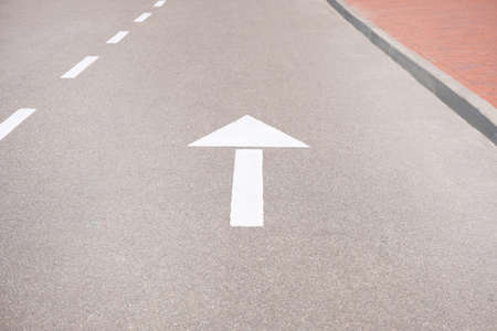 Forward signs on the road. White arrow marking pointing ahead on asphalt.