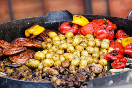 Frying pan with fried potatoes, sausages, mushrooms and pepper.Street food and outdoor cooking concept.の写真素材