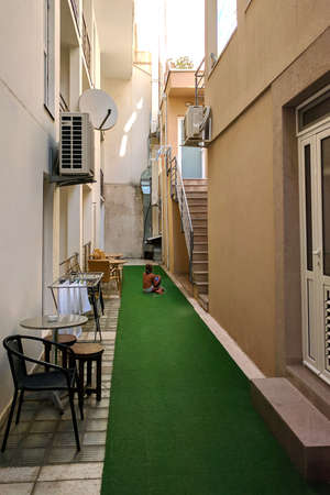 Llittle girl sitting on floor in a narrow yard between houses. Summer in Montenegro.の写真素材