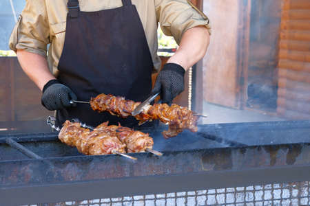 Man is frying meat on an open fire. Street food and outdoor cooking concept.の写真素材