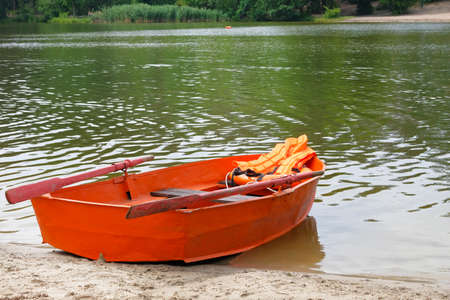Outfit of lifeguard on water in summer boat, life jacket, lifebuoy in orange color. Help in water.