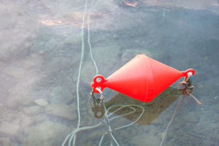 Red anchor buoy lies on clear sea  water.の写真素材