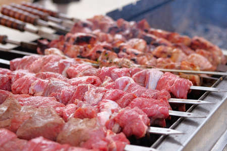 Shish kebab from pork and beef on coals. Fried pieces of meat on skewers are roasted on a grill. Barbecue meat background.の写真素材