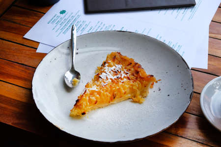 Slice of freshly baked apple open pie on porcelain plate on table in cafe, close up.の写真素材