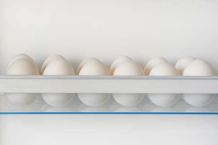 White raw chicken eggs from fridge. Eggs on shelf of refrigerator. Horizontal view.の写真素材
