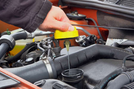 Automobile maintenance concept. Driver checking oil level in car engine. Close up.