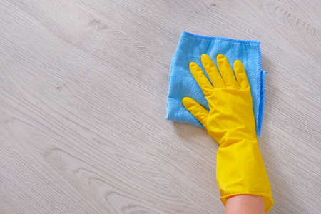 Commercial cleaning company concept. Hand in rubber protective glove with blue microfiber cloth is...