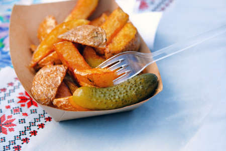Potatoes with pickled cucumber in food market. Ukrainian national food. Street food and outdoor...
