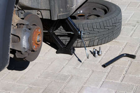 Man picks up car jack to change tire. Technicians are changing tires. Car repair concept.