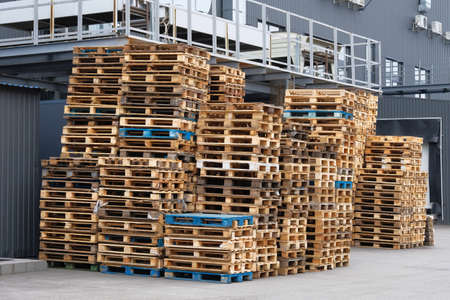 Stacks of colorful rough wooden pallets at warehouse in industrial yard. Wooden pallets for...
