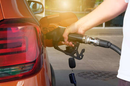 Petrol station pump. Pumping gasoline fuel in orange car at a gas station. To fill orange car with...