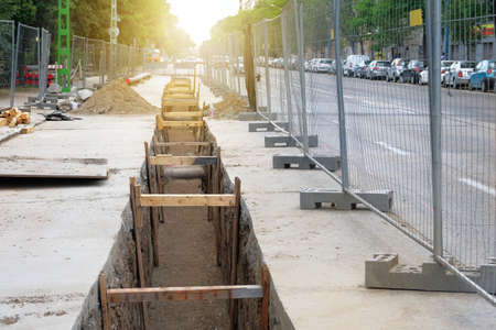 Engineering works. Repair of urban underground communications. Laying communications underground. Deep hole for pipe laying. Underground pipe installation.の写真素材