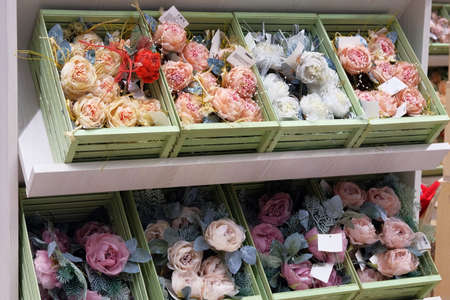 Christmas artificial flowers for decoration prepared for sale in supermarket. Variety of colorful decoration on wooden shelves of large shop.の写真素材