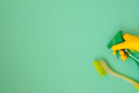 Flat lay cleaning products and brush, copy space. Hand in yellow rubber protective glove. Cleaning service concept. Top view.の写真素材