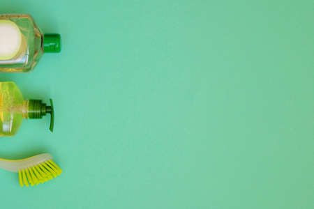 Cleaning products on green background. Detergents and brush. Housework and household concept. Top view. Copy space.の写真素材
