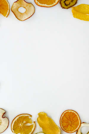 Oranges, apples, kiwis,  mango chips on white background with copy space. Healthy vegan vegetarian fruit snack or ingredient for cooking. Vertical view.の写真素材