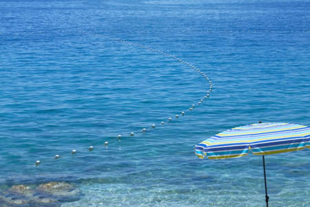 Blue umbrella for relax and comfort on sea beach. Happy summer of vacations and tourism. Background of summer waterscape.の写真素材