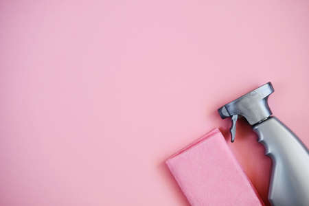 Cleaning agent in a spray in a gray bottle. Top view of cleaning product and cloth on pink background. Closeup. Copy space.の写真素材