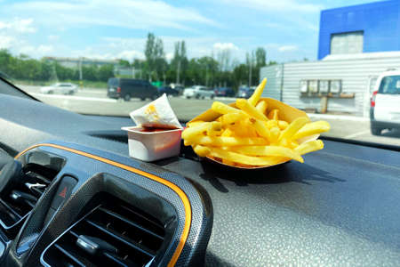 French fries and ketchup for lunch. Snack on console in auto. Lunch break while traveling by car. Takeaway, street food.の写真素材