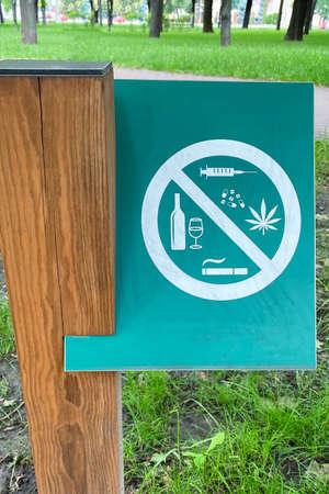 Sign prohibiting alcohol, cigarettes, drugs on background of green grass in park. Symbol on metallic plate.の写真素材