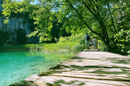 Summer landscapes along lake in traveling trip. Wooden vintage bridge walkway. Tourists is walking.の写真素材