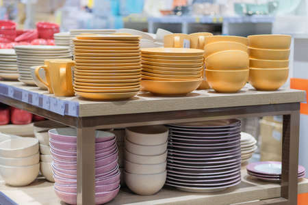 Dishes are sold at the store. Rows of different yellow bowls and plates for home on shelves in a supermarket.の写真素材