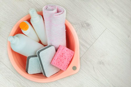 Detergent bottles with washcloths in a pink basin on a wooden background. Top view. Isolate on a white background. Copy space.の写真素材