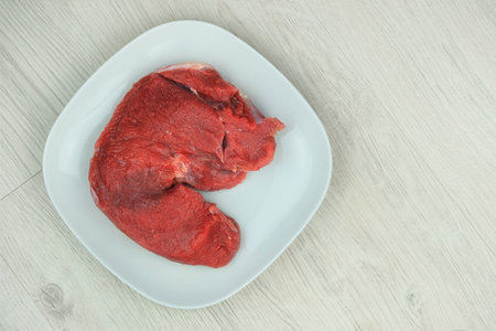 Beef pulp in plate in white wood background. Raw meat for cooking.の写真素材