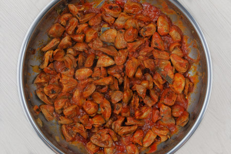 Chicken hearts with parsley and tomatoes are fried in a metal pan. Home cooking or culinary....