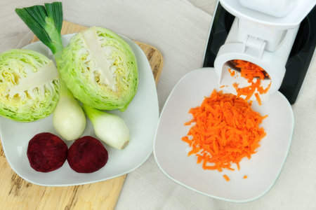 Ð¡arrots in a vegetable cutter on kitchen table. Chopped carrots is falling into a bowl. Homemade healthy food.の写真素材