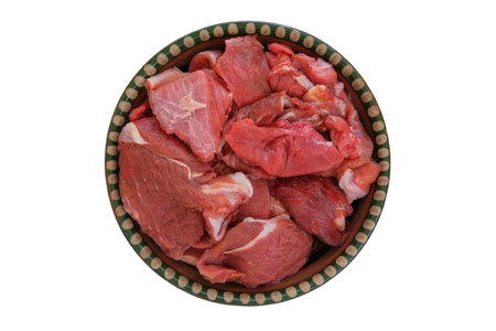 Pieces of meat on a rustic  dish isolated on white background. Raw beef for cooking. Top view.の写真素材